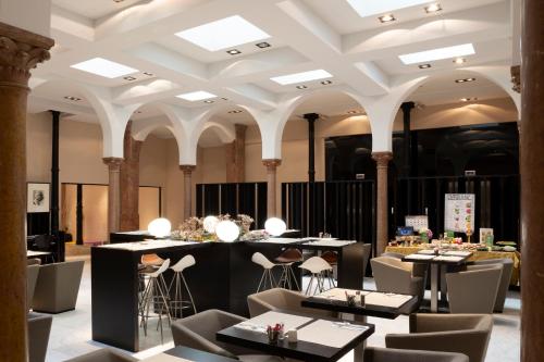 un ristorante con tavoli, sedie e soffitto di Petit Palace Plaza Málaga a Málaga
