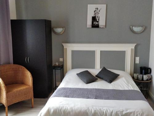 コンカルノーにあるHôtel Les Grands Voyageursのベッドルーム1室(枕2つ、椅子付)