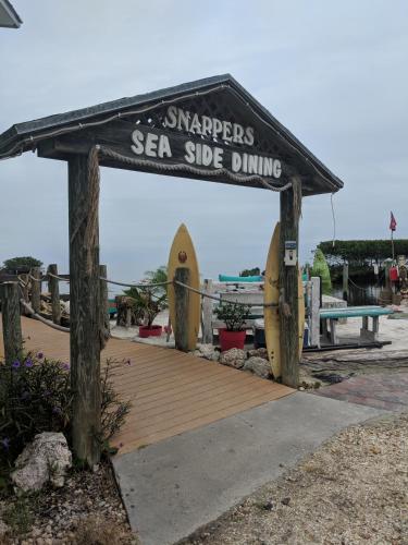 基拉戈的住宿－Snappers Key Largo，木板路,上面标有重新宣传海边用餐的标志