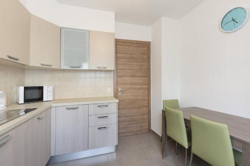 uma cozinha com armários brancos e cadeiras verdes em Girasole by Quokka 360 - quiet two-bedroom apartment close to the centre em Lugano
