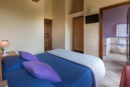 a bedroom with a blue bed and a bathroom at Badia Agriturismo in La Torraccia