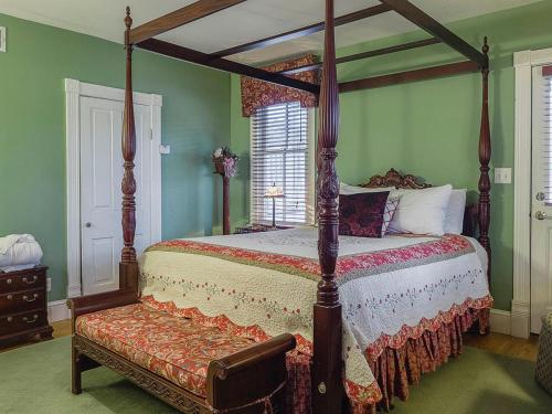 um quarto com uma cama de dossel e um banco. em George Brooks House B&B em Saint Michaels