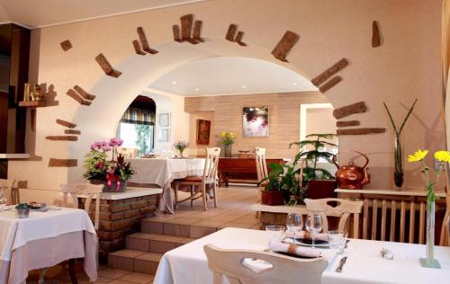 a restaurant with white tables and a large archway at Logis Burnel Et La Cle Des Champs in Rouvres-en-Xaintois