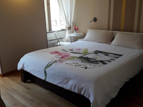 a bedroom with a white bed with flowers on it at La Luna nel Borgo in Brugnato