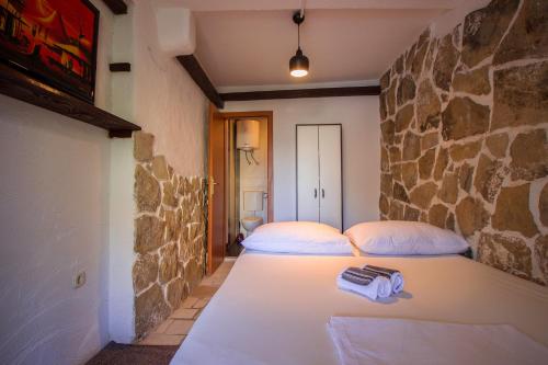 1 dormitorio con 2 camas y pared de piedra en Apartments Hajdi, en Duće