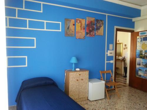 een blauwe slaapkamer met een bed en een stoel bij B&B Intrabartolo in Trapani