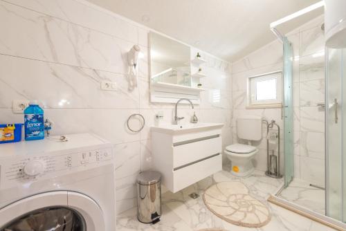 ein weißes Badezimmer mit einem Waschbecken und einer Waschmaschine in der Unterkunft Tranquility and Nature in 4 Bedroom with Sea View in Mokošica