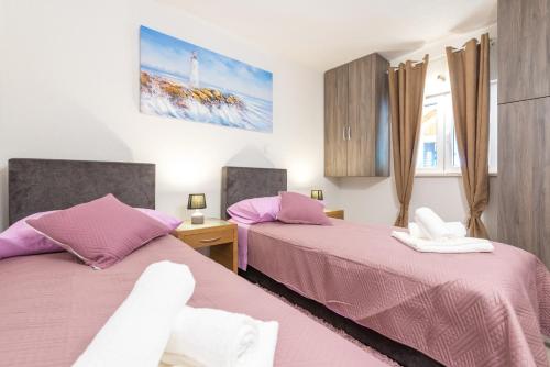 2 Betten in einem Schlafzimmer mit rosa Bettwäsche in der Unterkunft Tranquility and Nature in 4 Bedroom with Sea View in Mokošica