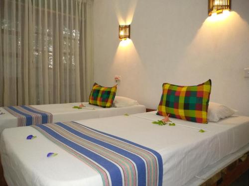 two beds with colorful pillows in a room at Grand freedom in Sigiriya
