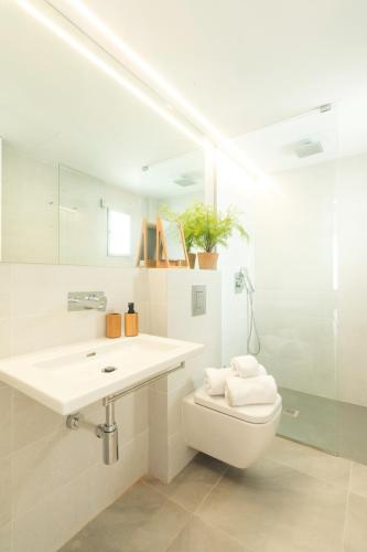 a white bathroom with a sink and a toilet at Sea Breeze Apartments in Cala Millor