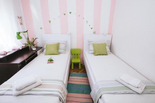 two beds in a small room with a green chair at Apartment Ema in Šibenik