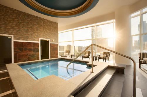 a swimming pool in a building with a table and chairs at Fairmont Austin Gold Experience in Austin