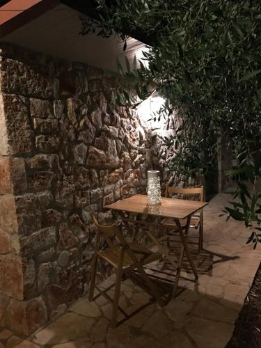 a wooden table and chairs in front of a stone wall at Aria di Casa Country Resort in Alberobello