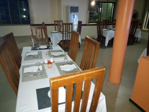 a dining room with a white table and wooden chairs at Citilodge Hotel & Conference Centre Newly Renovated in Abuja
