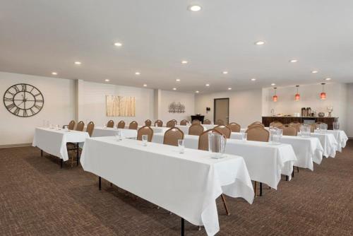 a conference room with white tables and chairs and a clock at Country Inn & Suites by Radisson, Baxter, MN in Baxter
