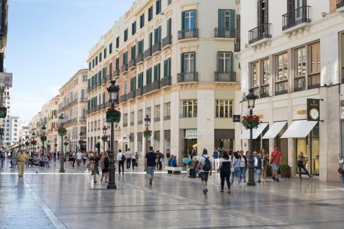 a group of people walking down a city street at Petit Palace Plaza Málaga in Málaga