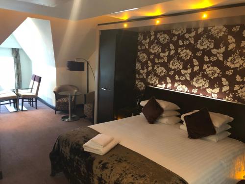a bedroom with a large bed with a floral wallpaper at The BlueBell Hotel in Neath