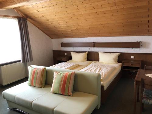 a bedroom with a large bed and a couch at Gästehaus Rehwinkel in Allenbach