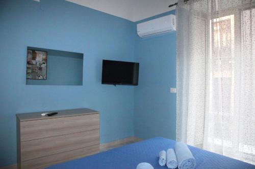 a blue bedroom with a bed and a tv on the wall at Patrì House in Catania