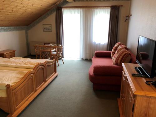 a bedroom with a bed and a couch and a television at Gästehaus Rehwinkel in Allenbach