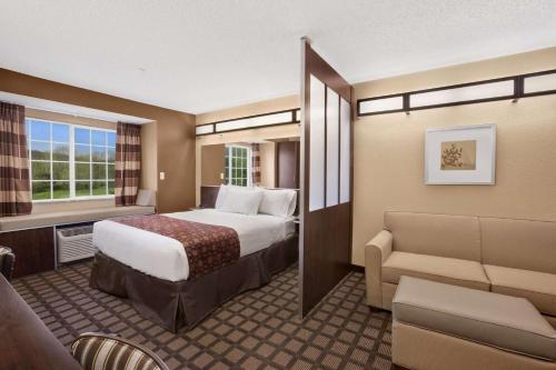 Microtel Inn & Suites-Sayre, PA في Sayre: غرفه فندقيه بسرير واريكه