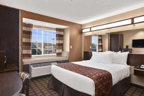 SayreにあるMicrotel Inn & Suites-Sayre, PAの大きなベッドと窓が備わるホテルルームです。