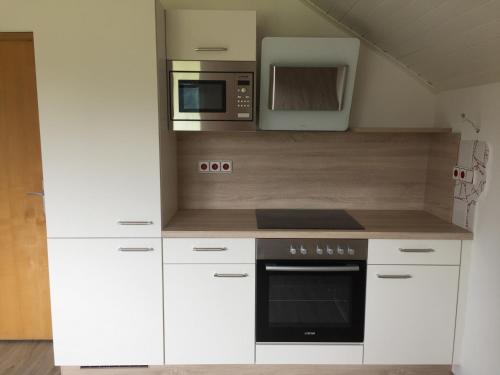 a kitchen with white cabinets and a microwave at Ferienwohnung Trattnig in Gassen
