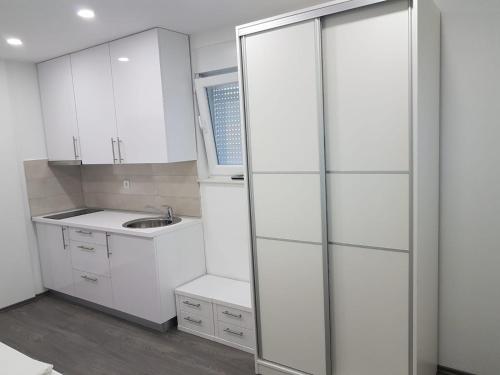 a white kitchen with a sink and a sliding glass door at Apartments Vinko in Novalja