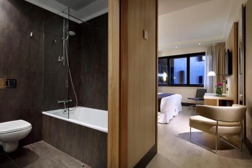 a bathroom with a tub and a toilet and a sink at Occidental Bilbao in Bilbao