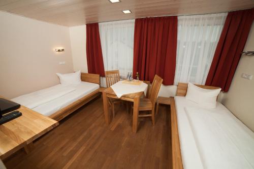 a room with two beds and a table and chairs at Goldener Stern in Dingolfing