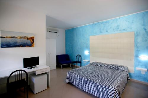 a bedroom with a bed and a desk and a tv at Hotel Parco Carabella in Vieste