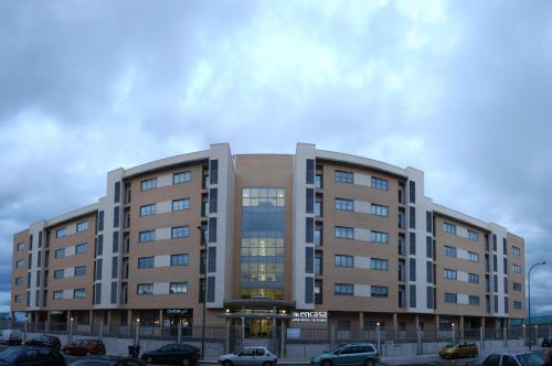 a large building with cars parked in a parking lot at Aparthotel Encasa in Madrid