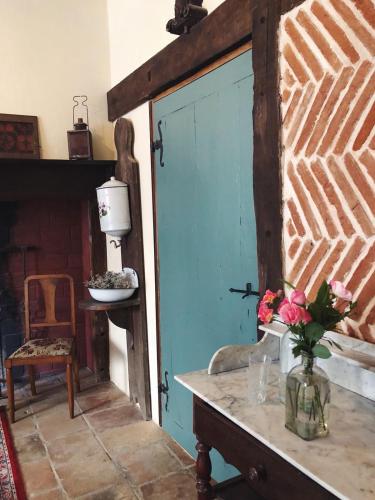 une porte bleue dans une pièce avec une table et des fleurs dans l'établissement Auberge Lion D'Or, à Saint-Antonin