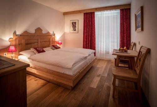 a bedroom with a bed and a desk and a window at Appartementhaus Sapelza in Dobbiaco