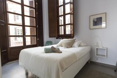 Apartamentos Málaga Picasso في مالقة: سرير أبيض في غرفة بها نوافذ