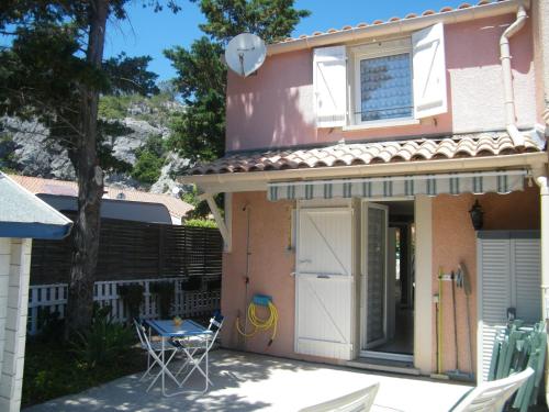 une maison rose avec une porte blanche, une table et des chaises dans l'établissement Villa T3, 4 personnes, Le Clos du Soleil, à Narbonne-Plage