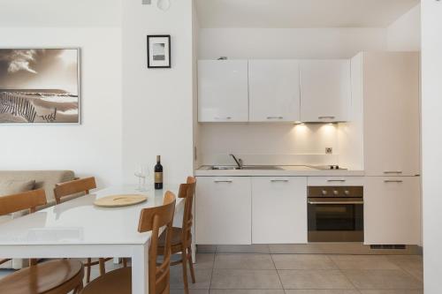 a kitchen with white cabinets and a table with a dining room at Prestige Apartments by Quokka 360 - spacious flats with terraces in Lugano