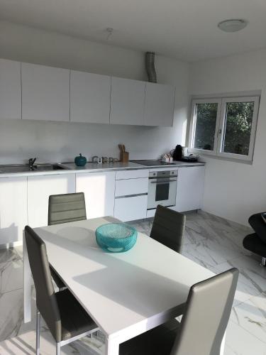 a white kitchen with a white table and chairs at Roggia Apartments by Quokka 360 - central flats with parking space in Lugano