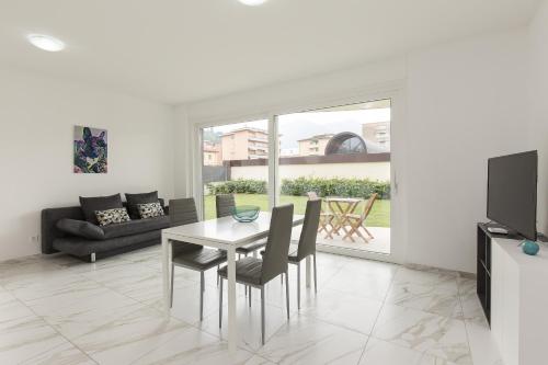 sala de estar con mesa, sillas y TV en Roggia Apartments by Quokka 360 - central flats with parking space, en Lugano