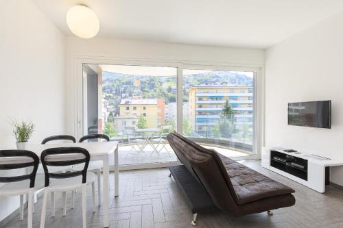 a white dining room with a table and chairs at Roggia Apartments by Quokka 360 - central flats with parking space in Lugano