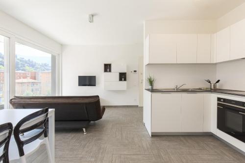 a kitchen with white cabinets and a couch in a room at Roggia Apartments by Quokka 360 - central flats with parking space in Lugano