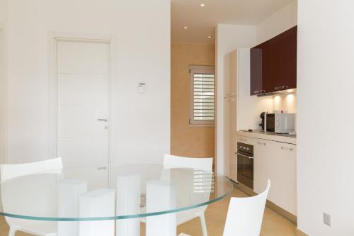a kitchen with a glass table and white chairs at Prestige Apartments by Quokka 360 - spacious flats with terraces in Lugano