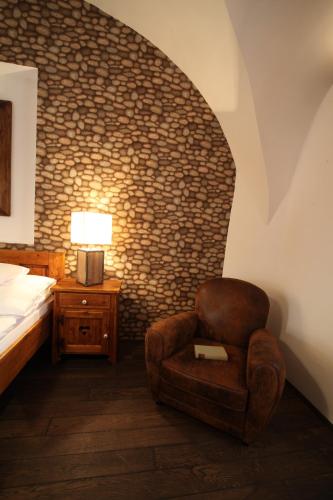 a bedroom with a chair and a bed and a lamp at Régi Posta Hotel és Étterem in Debrecen