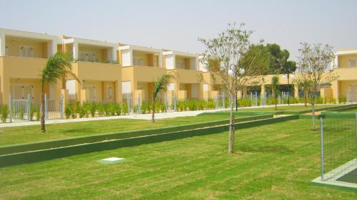a large yellow building with trees in front of it at Residence Mar Mediterraneo in Quartu SantʼElena