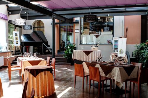 un ristorante con tavoli, sedie e pianoforte di Hotel Dei Pittori a Torino