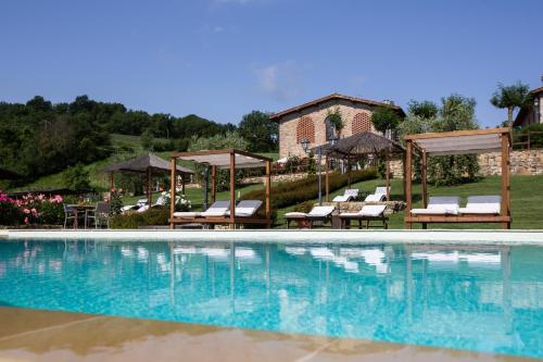einen Pool mit Stühlen und Sonnenschirmen neben einem Haus in der Unterkunft Agriturismo Vita Nova in Vicchio