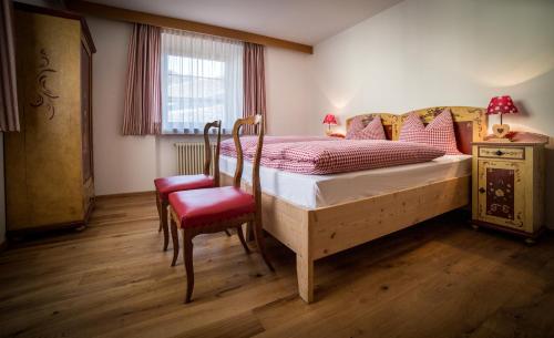 a bedroom with a bed and a chair and a window at Sapelza Appartementhaus in Dobbiaco