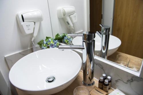 La salle de bains est pourvue d'un lavabo blanc et d'un miroir. dans l'établissement Brekner Rooms, à Sibiu