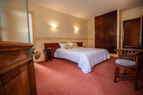 a bedroom with a white bed and a chair at Hôtel Terminus in Cahors