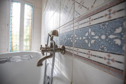 a bathroom with a bath tub with a hose at Hôtel Terminus in Cahors